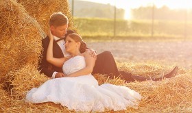 Bridal couple sitting on bales of stacked hay. barn wedding ideas