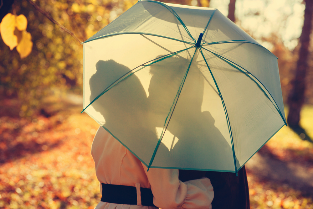 Cute Save The Date Idea With A Couple Sharing A Kiss Behind An Umbrella. Funny, Cute Save The Date Photo Ideas: Picture and Wording Examples